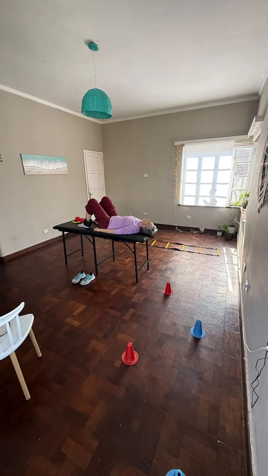 Una persona entrena en camilla, con conos y una escalera de agilidad en el piso